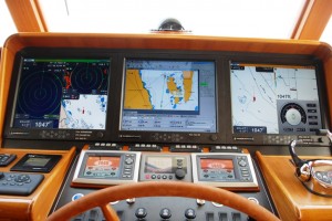 Here's the center section of the instrument panel as seen from the helm seat.  The three primary screens are 17", with the Nobeltec chart plotting software in the center screen, and our Furuno NavNet 3D hardware/software running on the two outside screens.  The left screen is usually split 3 ways, with a large radar image on the left (set at 1 mile range), a small radar image in the upper right (set at 3 mile range), and a small image chart plot in the lower right.  The rightmost screen is also split three ways, with a chart plot image on the left, a visual depth guage on the upper right, and a graphic compass on the lower right.  The engine control monitors are in the left and right foreground, and the autopilot control screen in the center.