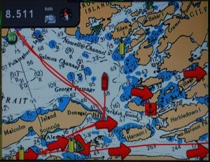 Our Furuno chart plotter screen maps our crossing of Queen Charlotte Strait.  Flying Colours is the red boat icon in the center of the screen.  The previous week’s course to/from Sullivan Bay is the parallel red lines that snake up to the top left corner, illustrating the difference in today’s route.  Queen Charlotte Strait is rather shallow – typically with 2-digit depths, and to the left of our course are some rocks on a shoal that stick up at low tide, and are poised to punch a hole in you if you try to pass over them at high tide.  The big red arrows are current directions, giving us a small push as we depart Port McNeill and a side current (which only means we have to crab to correct for it) once we’re out in the strait.