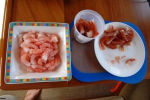 The plastic container in the center has prawns ready to peel; the plate on the left has peeled prawns.  They’ll be portioned out in batches of 30 (a dinner for two) for freezing in a pint Ziploc bag.