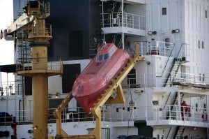 I also grabbed this close-up photo of a freefall lifeboat on another freighter.  Here you can more clearly see the type of boat this is, and the rails that it free falls after breaking free.  When you see the stern of a freighter up close you can tell just how high these things are off the water – and according to the YouTube video, they’re free falling at 35MPH when they hit the water.  You’d really need to be buckled in securely to survive this impact, and I’ll bet there is still some risk associated with it.  You can get a sense of the size of these lifeboats if you look at the guy standing at the railing in the lower right of the photo.